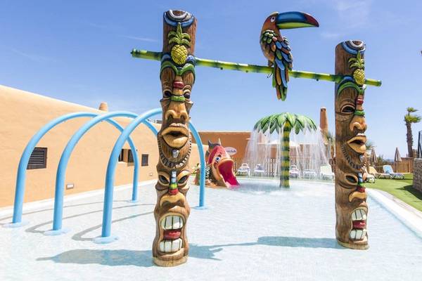 Tropische Wasserlandschaft im Cala Martina by Llum Hotel mit bunten Tiki-Figuren und Wasserrutsche.