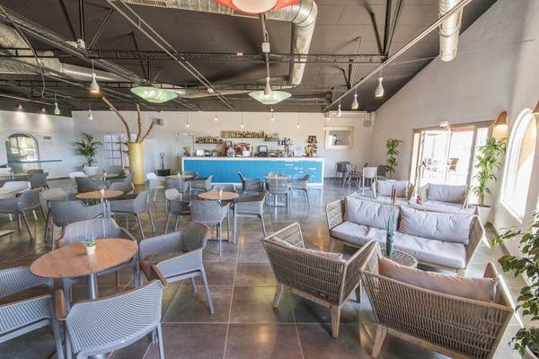 Innenbereich des Cala Martina by Llum Hotels mit Tischen, Stühlen und einem blauen Tresen.