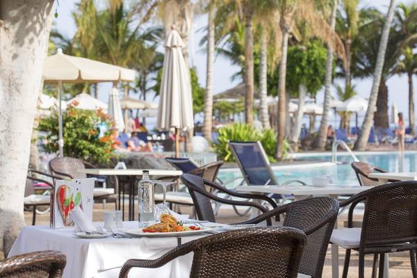 Außenbereich des Hipotels La Geria mit Tischen und Stühlen am Pool.