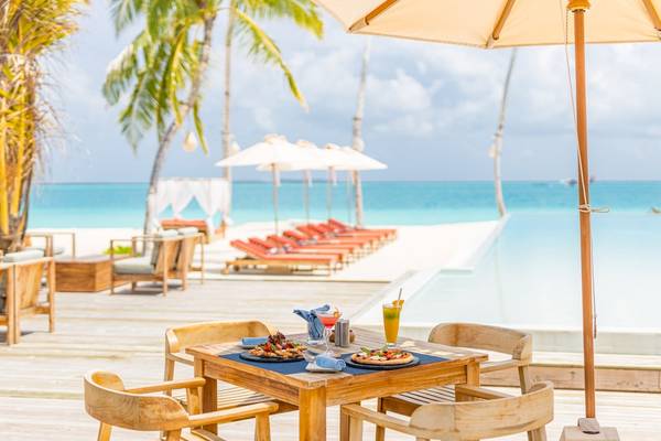 Terrasse des Sun Siyam Iru Veli Hotels mit Esstisch und Getränken vor einem Pool