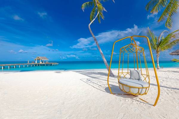 Strand mit Hängematte und Hotel Sun Siyam Iru Veli im Hintergrund