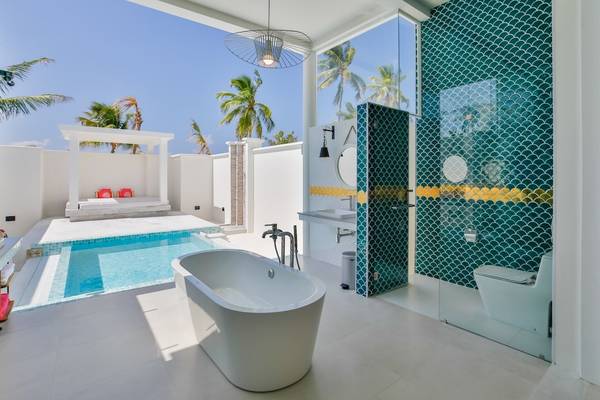 Ein Badezimmer mit Badewanne und Pool im Sun Siyam Iru Veli Hotel.