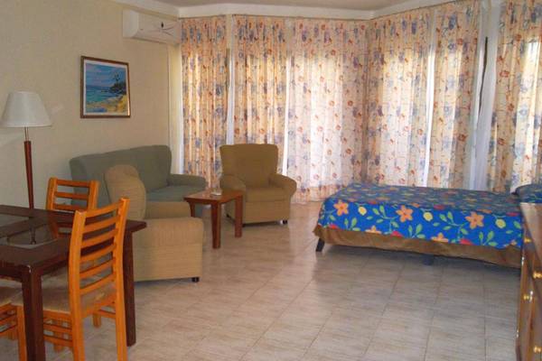 Ein Hotelzimmer mit Tisch, Stühlen, Couch, Sessel, Lampe und Bett im Roc Arenas Doradas Hotel.