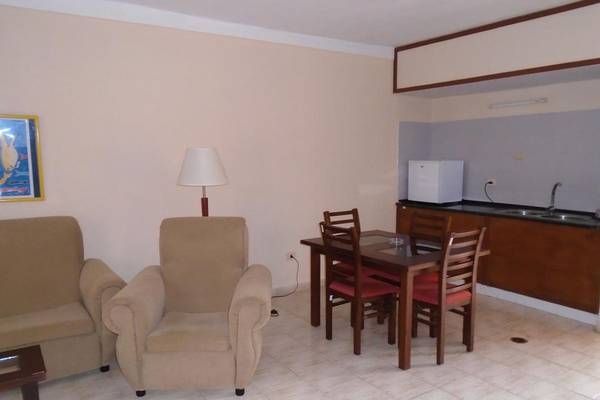 Das Wohnzimmer des ROC Arenas Doradas Hotels mit Sitzmöbeln, Tisch und Lampe.