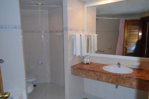 Ein Badezimmer des ROC Arenas Doradas Hotels mit einer Dusche, Toilette, Waschbecken und Spiegel.