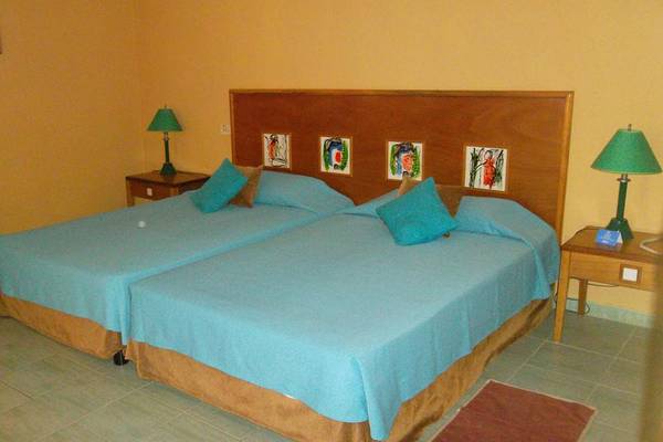 Zwei Betten mit blauen Laken in einem gelben Schlafzimmer des ROC Arenas Doradas Hotels.
