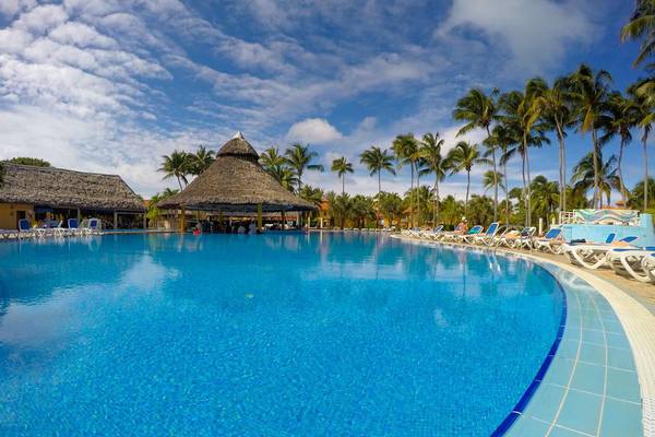 Außenpool des ROC Arenas Doradas Hotels mit Lounge-Stuhlreihen und Palmen.