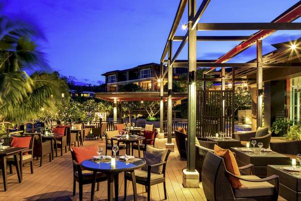 Terrasse des Pullman Phuket Panwa Beach Resort mit abendlicher Atmosphäre, Tischen und Stühlen im Freien.