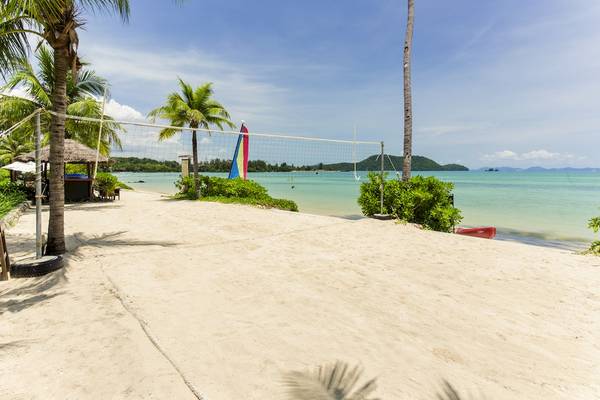 Ein Volleyballplatz am Strand des Pullman Phuket Panwa Beach Resort mit Palmen und Meer im Hintergrund.