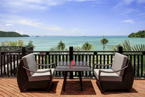 Ausblick auf das Meer von der Terrasse des Pullman Phuket Panwa Beach Resort mit zwei Rattan-Stuhls und einem Tisch.