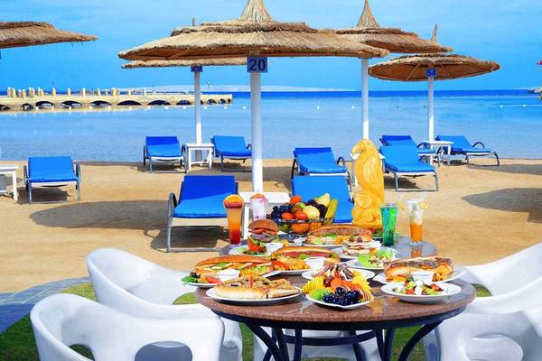 Buffet am Strand des Pickalbatros Dana Beach Resort mit vielen Speisen und Sonnenschirmen.