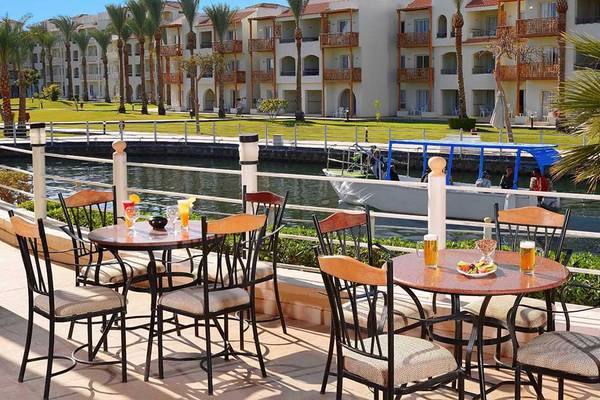 Terrasse des Pickalbatros Dana Beach Resorts mit Blick auf einen Kanal und Booten.