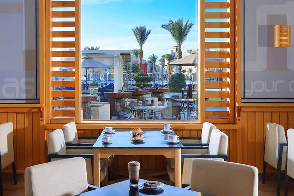 Innenansicht des Restaurants im Pickalbatros Dana Beach Resort mit Blick auf die Terrasse und Palmen.