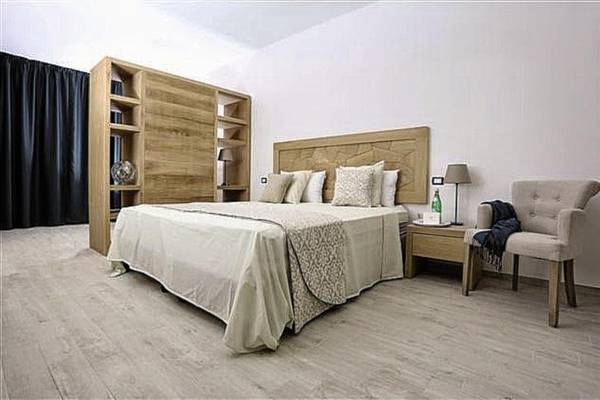Schlafzimmer im Marana Hotel mit Doppelbett, Nachttisch, Lampe und Sessel.