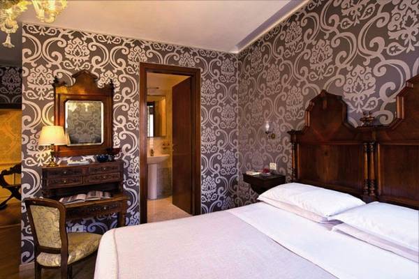 Schlafzimmer im Casa Nicolo Priuli Hotel mit Bett, Nachttisch, Stuhl und Wanddekoration.