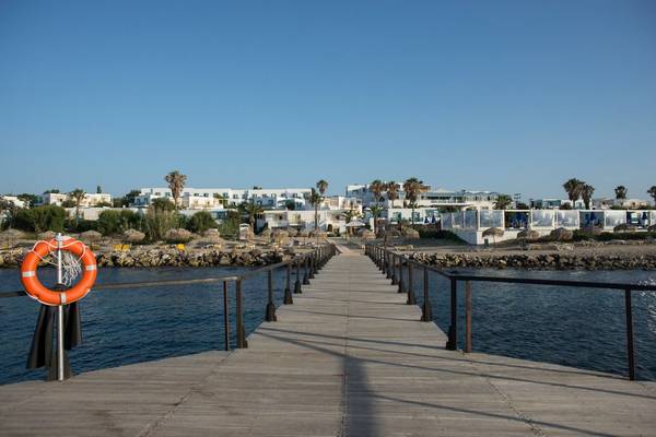 Holzsteg am Mastichari Bay Hotel mit Rettungsring und Blick auf weiße Gebäude