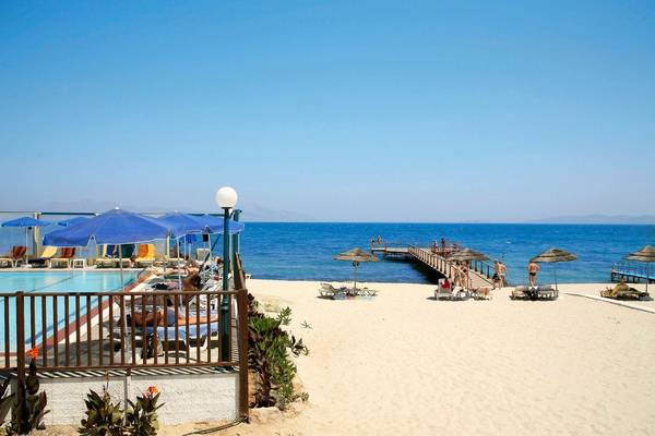 Strandszenerie des Mastichari Bay Hotels mit Sonnenschirmen, Liegestühlen und Pool