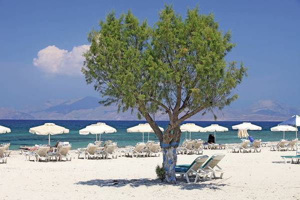 Strand des Mastichari Bay Hotels mit weißen Sonnenliegen und Schirmen