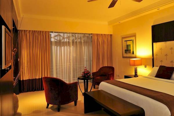 Schlafzimmer im Le Meridien Ile Maurice Hotel mit einem Bett, Sesseln, Tisch und Lampe.