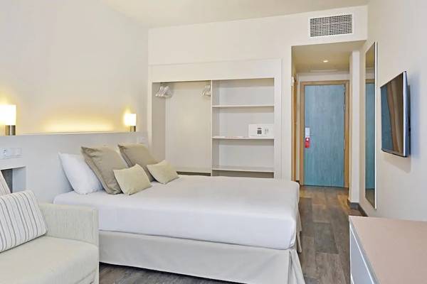 Innenansicht eines Hotelzimmers im Sol Barbados mit einem Bett, Sofa, Lampen und Fernseher.