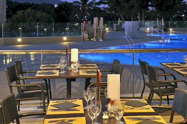 Außenbereich des Sol Barbados Hotels mit beleuchtetem Swimmingpool und gedeckten Tischen.