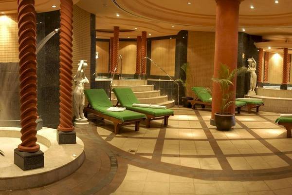 Wellnessbereich im Le Meridien Ile Maurice Hotel mit grünen Liegen, Statuen und Pflanzen.