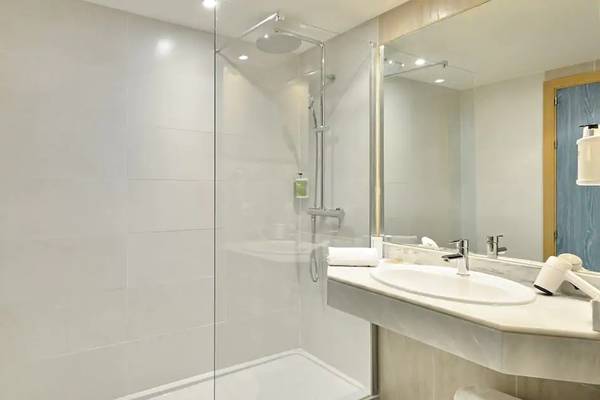 Badezimmer im Sol Barbados Hotel mit Glasdusche, Waschbecken und Spiegel.