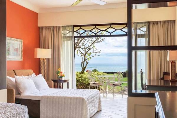 Suite im Le Meridien Ile Maurice mit Meerblick, zwei Betten, Tisch, Stühlen und Balkon.