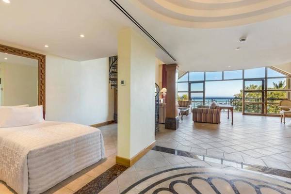 Innenansicht eines Zimmers im Le Meridien Ile Maurice Hotel mit Bett, Spiegel und Balkon mit Meerblick.