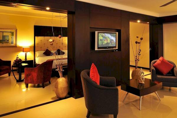 Inneneinrichtung einer Suite im Le Meridien Ile Maurice Hotel mit einem Fernseher, Möbeln und einem Bett.