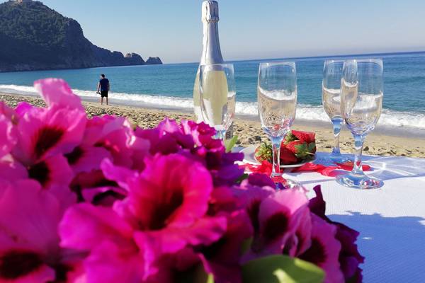 Strandtisch mit Blumen, Getränken und Meer im Hintergrund am Riviera Hotel & Spa