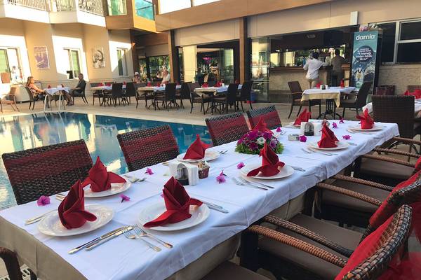 Poolside-Diningtisch im Riviera Hotel & Spa mit roten Servietten und Blumendekoration.