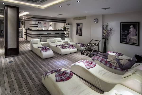 Lounge-Bereich im Riviera Hotel & Spa mit weißen Liegestühlen und einem Gast, der entspannt.