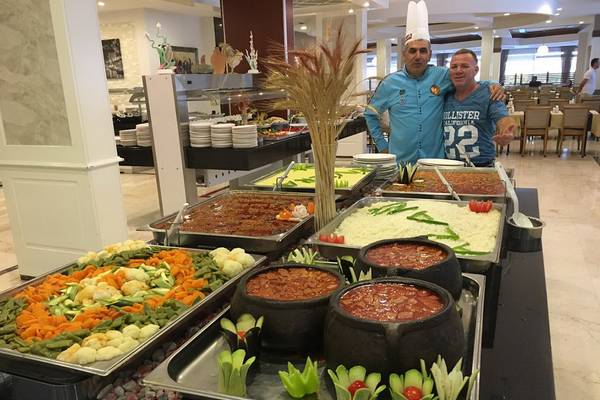 Buffet im Riviera Hotel & Spa mit verschiedenen Gerichten und zwei Männern im Hintergrund.
