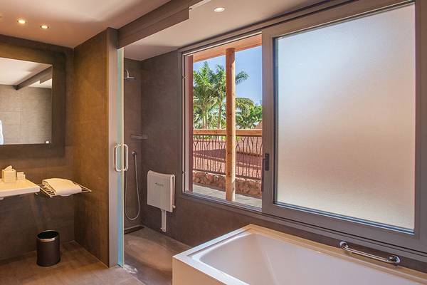 Badezimmer im Lopesan Baobab Resort mit Badewanne, Waschbecken und großer Fensterfront.