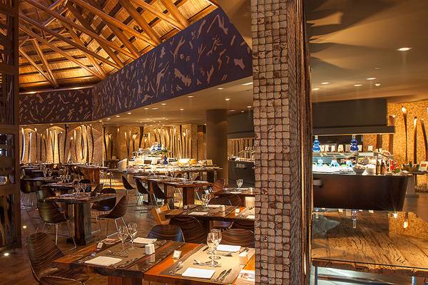 Innenansicht des Lopesan Baobab Resorts Restaurants mit hölzernen Tischen und Stühlen.