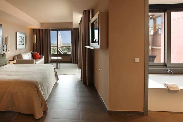 Hotelzimmer im Lopesan Baobab Resort mit Bett, Sofa, Tisch und Ausblick auf Terrasse und Landschaft.