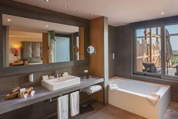 Badezimmer im Lopesan Baobab Resort mit großer Badewanne, Waschbecken, Spiegel und Aussicht.
