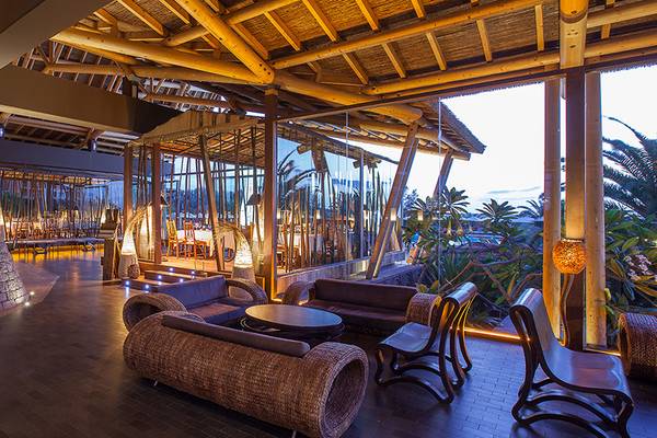 Innenbereich des Lopesan Baobab Resorts mit Holzstrukturen, Sitzmöbeln und Aussicht auf Außenbereiche.