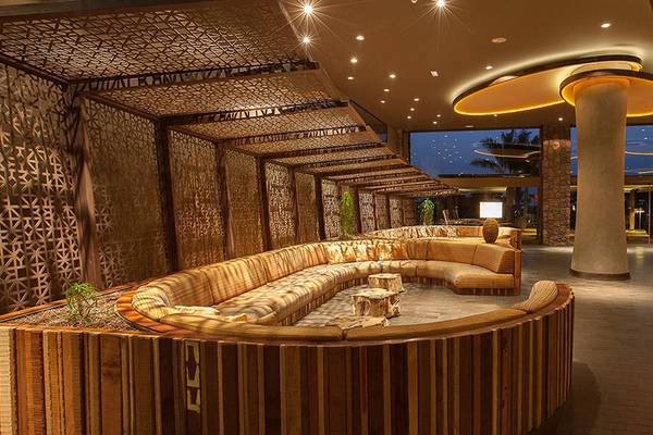 Innenbereich des Lopesan Baobab Resorts mit einer großen, gebogenen Couch und dekorativen Wänden.