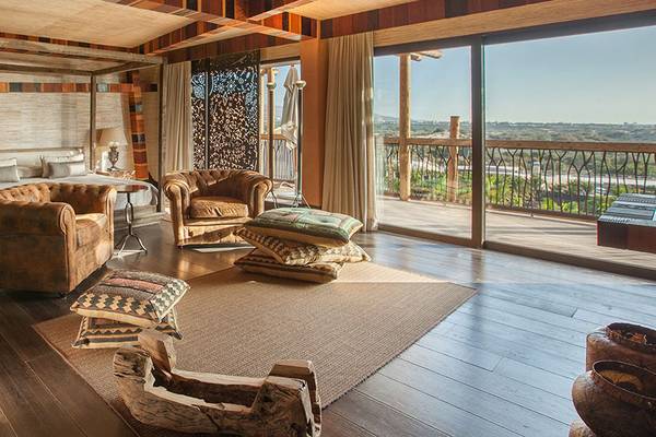 Innenansicht einer Suite im Lopesan Baobab Resort mit großem Bett, Wohnzimmerbereich und Aussicht auf die Landschaft.