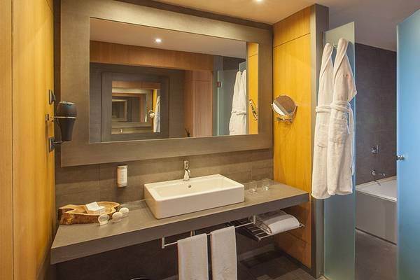 Badezimmer im Lopesan Baobab Resort mit einem Waschbecken, Spiegel, und Badewanne.
