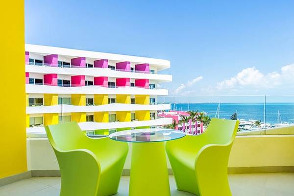 Ausblick von der Balkon des Temptation Cancun Resorts auf das Meer und eine bunte Hotelfassade.
