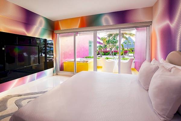Schlafzimmer im Temptation Cancun Resort mit bunten Wänden, einem großen Bett und einer Terrasse