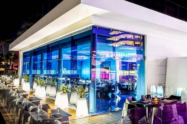 Außenbereich des Temptation Cancun Resorts bei Nacht mit blauen Lichtern und runden Tischen.