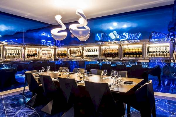 Innenbereich des Temptation Cancun Resort Restaurants mit langem Tisch, blauen Wänden und Flaschen im Kühlschrank.