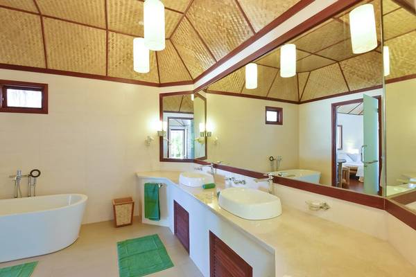 Badezimmer im Thulhagiri Island Resort mit zwei Waschbecken, Badewanne und Spiegeln.