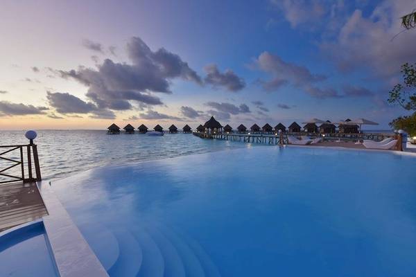 Abendstimmung am Außenpool des Thulhagiri Island Resorts mit Blick auf Wasservillen und Steg.