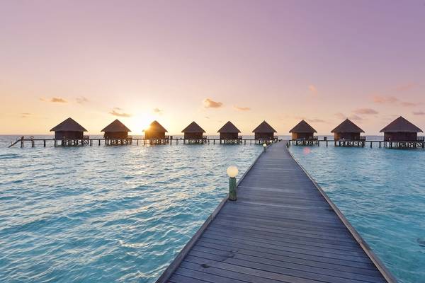 Thulhagiri Island Resort Wasserbungalows bei Sonnenuntergang mit rosa Himmel