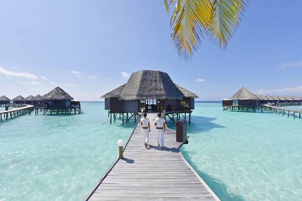 Zwei Personen auf einem Holzsteg des Thulhagiri Island Resorts in den Malediven.